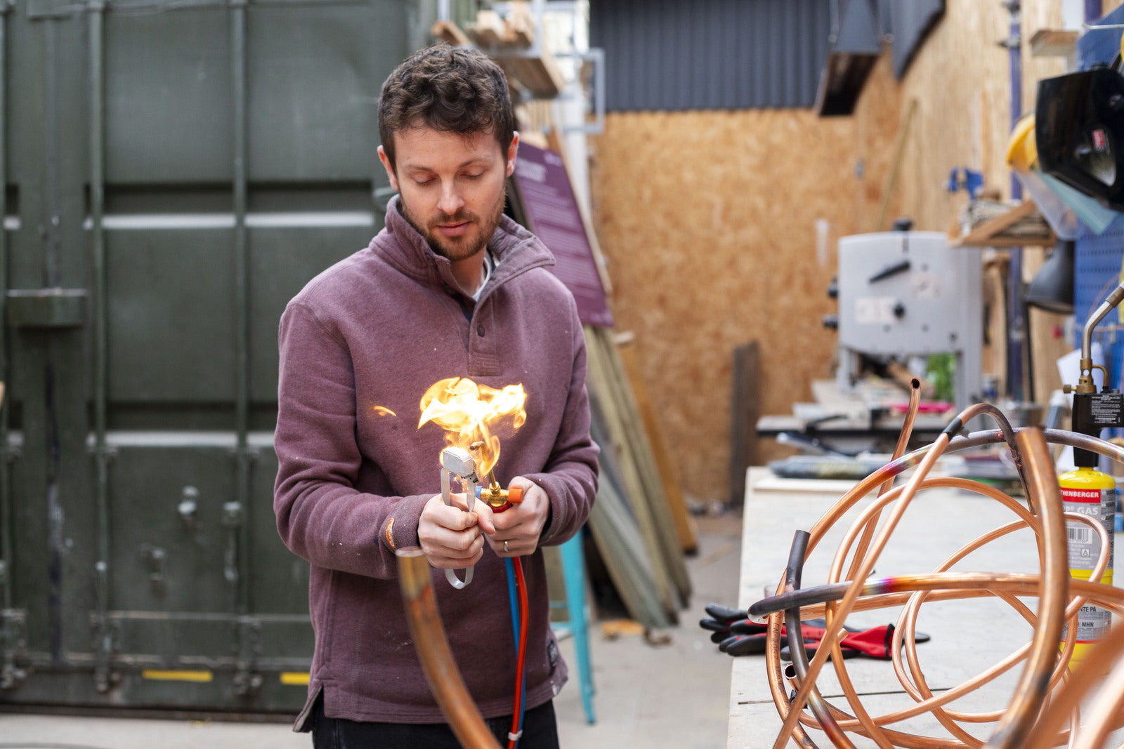 Contemporary sculptor Mark Beattie using a blowtorch in his studio, creating one of his signature abstract metal sculptures.