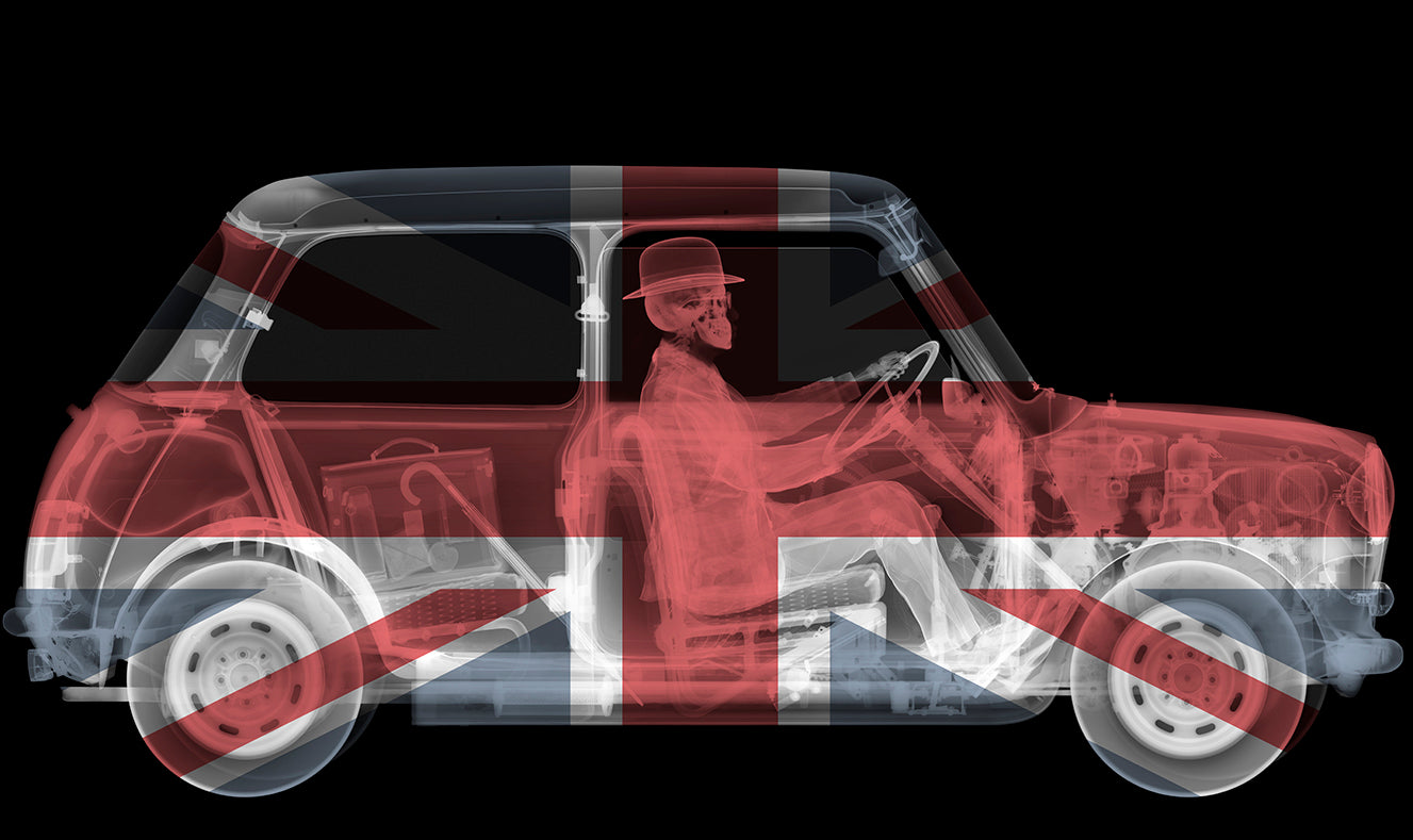 Nick Veasey standing with arms crossed in front of one of his iconic x-ray artworks, a black-and-white image of a 4x4 vehicle.