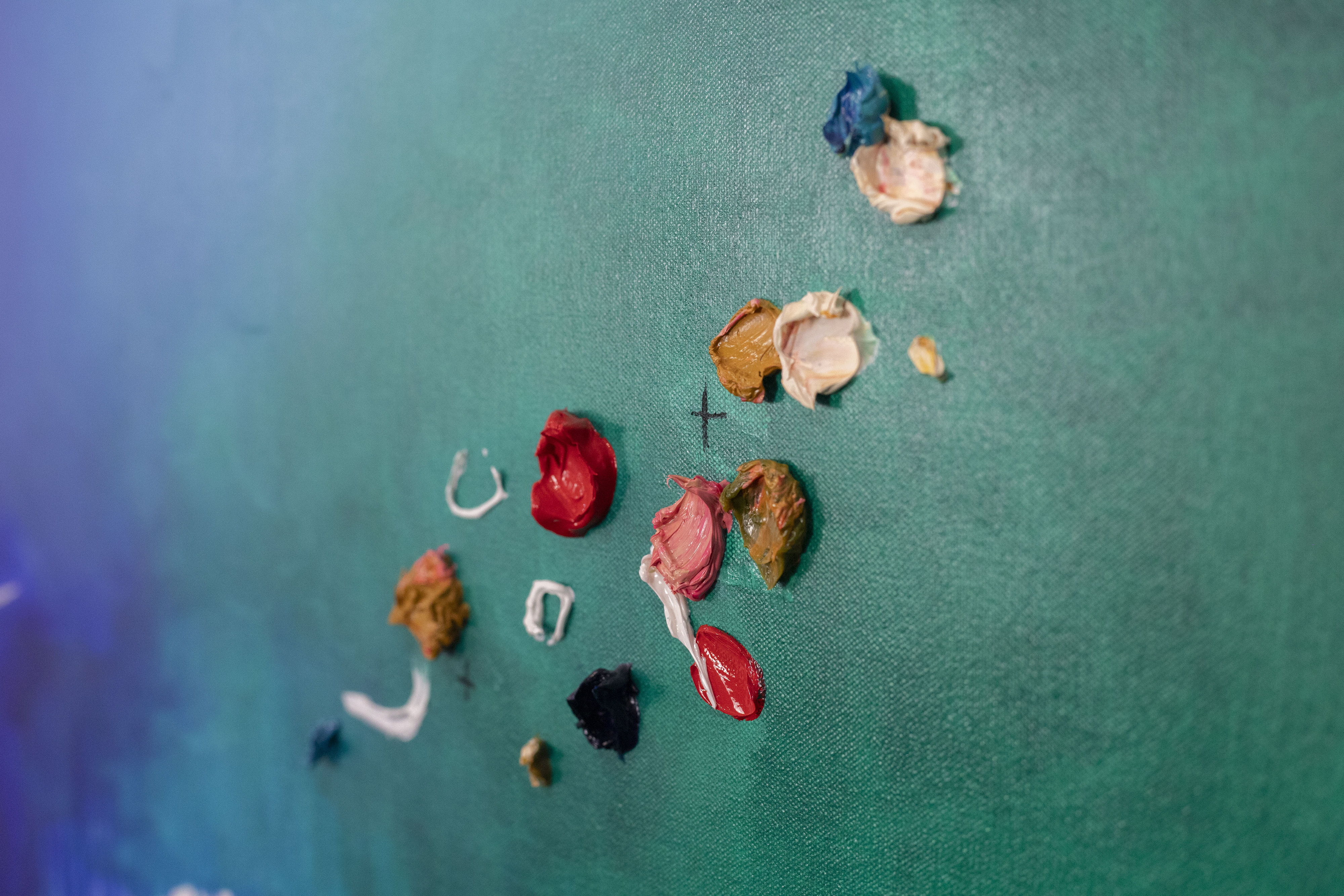 Piper Bridwell painting at an easel in her studio, surrounded by colourful abstract artworks on display